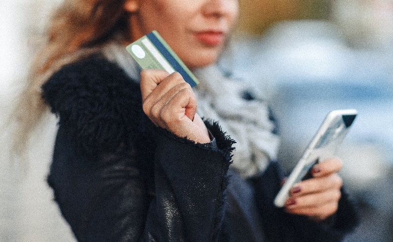 A woman holding a card and a phone